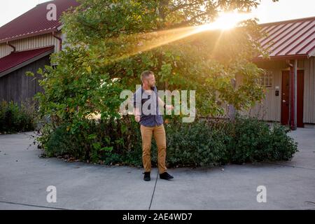 A happy man dances in front of his home at sunset in golden light Stock Photo