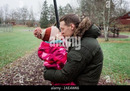 father kissing his daughter whilst playing outside in a park Stock Photo
