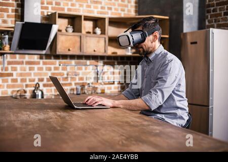 Professional businessman working on the laptop in VR device Stock Photo