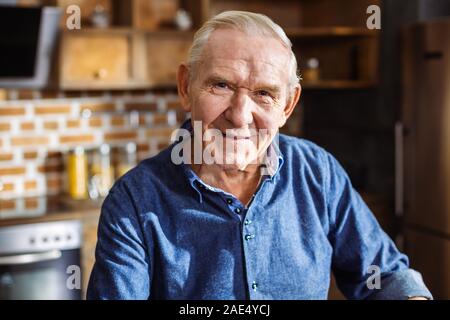 Portrait of pleasant aged man standing in the kitchen Stock Photo