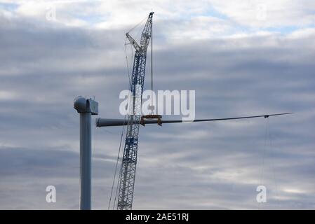 Mechanical cranes lift the blade of a wind turbine near the small village of Beltejar.Construction work continues on a new wind farm in Beltejar, north of Spain.  Spain is the fifth country in the world to install wind power, after China, USA Germany and India. During COP25, the Spanish president Pedro Sanchez pledged to reduce the level of CO2 emissions by 20% in the next years. Stock Photo