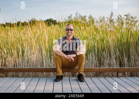 Front view portrait of confident man on boardwalk in wetlands park Stock Photo