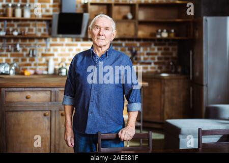 Serious aged man leaning on the chair Stock Photo