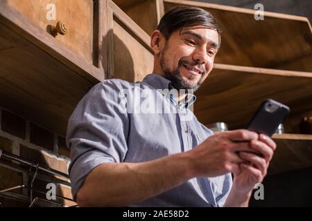 Low angle of cheerful young man using his smartphone Stock Photo
