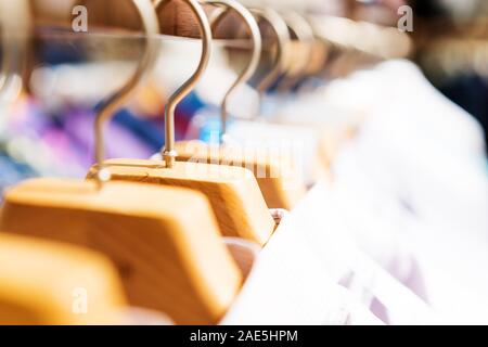 White Fashionable clothes on hangers in store Stock Photo