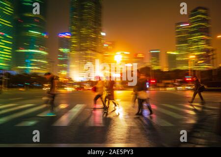 Abstract background of People across the crosswalk at night in Shanghai, China. Perfect background image of blurred night street with unrecognizable p Stock Photo