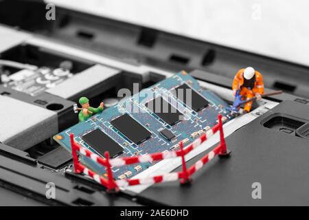 Miniature scale model construction workers installing RAM into the memory slot on a laptop computer Stock Photo