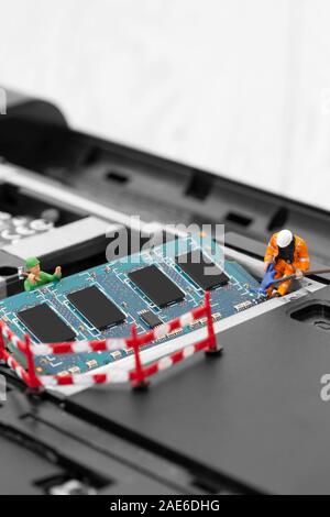 Miniature scale model construction workers installing RAM into the memory slot on a laptop computer Stock Photo