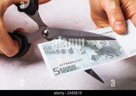 A man cuts five euros. Concept on the topic of devaluation of money in the country Stock Photo