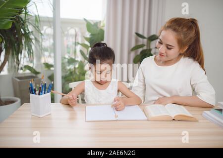 Asian mother and daughter doing home work together in living room Stock Photo