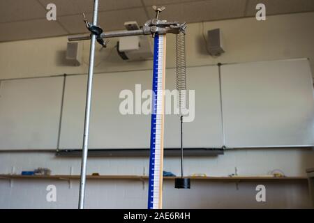 School science class demonstrating Hooke's Law with metal spring and weight Stock Photo