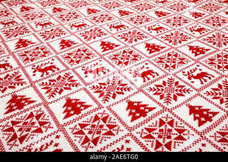 White knitted fabric with red  moose, fir tree and snowflake Scandinavian style geometric ornament cristmas background Stock Photo