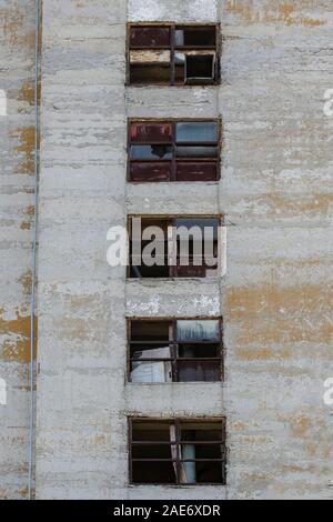 Old abandoned factory with broken windows and weathered Industrial building exterior. Leading lines composition concept of ruined past and future. Stock Photo