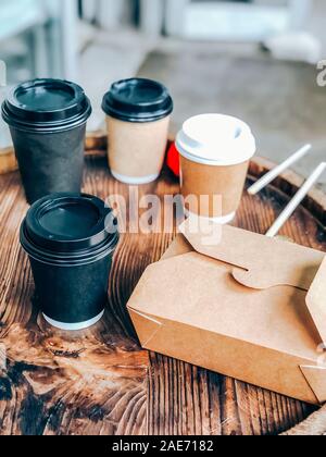 Coffee cups and street food craft paper container on a wooden outdoor table. Street market food and drinks take away waste problem concept. Mobile pho Stock Photo