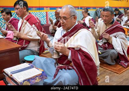 Devout Buddhist worshippers pray & ring bells at a monthly Throma Puja at a temple in Elmhurst, Queens, New York City. Stock Photo