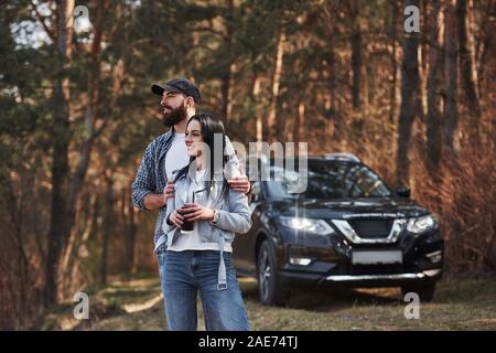 Nice weather today. Enjoying the nature. Couple have arrived to the forest on their brand new black car Stock Photo