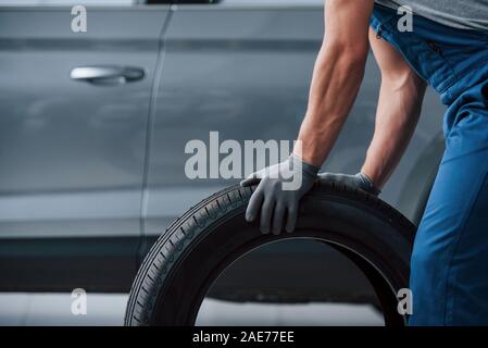 Replacement of winter and summer wheels. Mechanic holding a tire at the repair garage Stock Photo