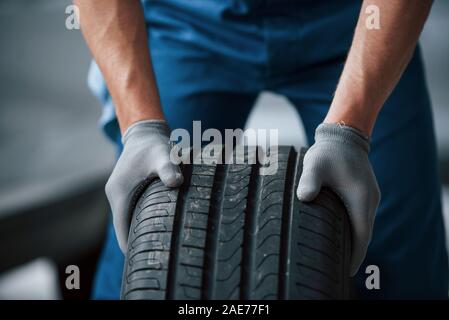 Dirt on the wheel. Mechanic holding a tire at the repair garage. Replacement of winter and summer tires Stock Photo