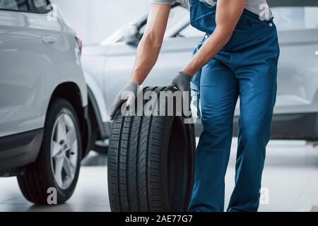 On my way. Mechanic holding a tire at the repair garage. Replacement of winter and summer tires Stock Photo