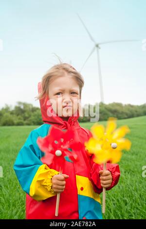 Boy with two pinwheels in front of wind farm. Stock Photo