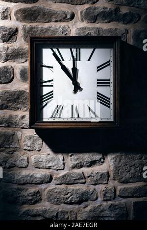 Square clock hanging on a stone wall. Stock Photo