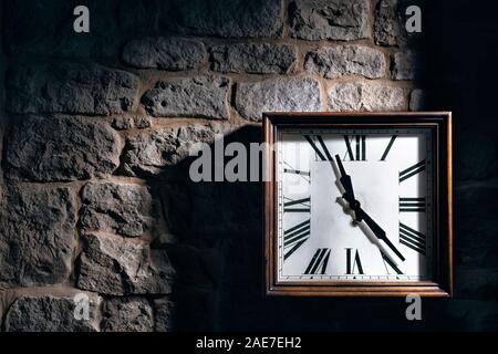 Square clock hanging on a stone wall. Stock Photo