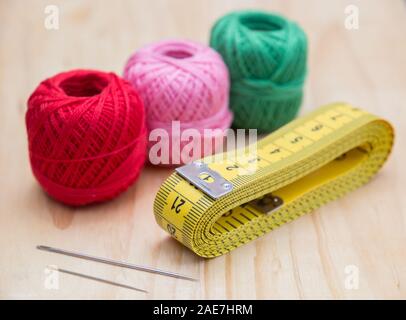 colored woolen thread and needles and meter close up on a wood background Stock Photo