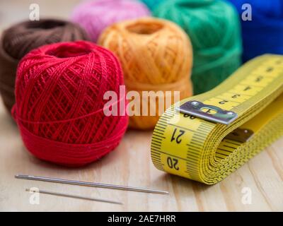 colored woolen thread and needles and meter close up on a wood background Stock Photo