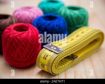 colored woolen thread and needles and meter close up on a wood background Stock Photo