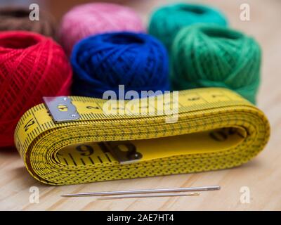 colored woolen thread and needles and meter close up on a wood background Stock Photo