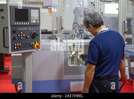 Worker control compact CNC lathe with robotic loading workpiece Stock Photo