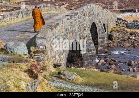 Visiting monk taking a photo photograph standing on old bridge Sligachan, Isle of Skye, Scotland, UK in March Stock Photo