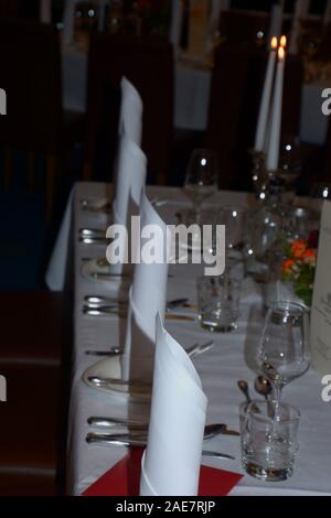 festive table decoration, white festive table setting with candles and noble cloth napkins Stock Photo