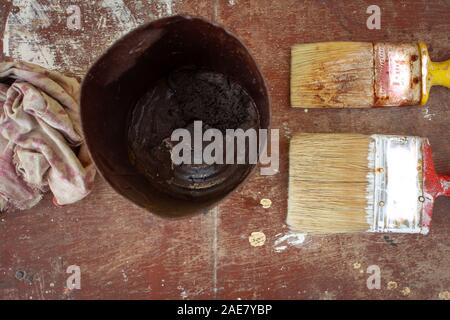 View of used paint brushes and the paint can over a wooden background Stock Photo
