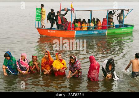 Pilgrims, mainly women, dressed in colorful Indian clothes having a ritual bath in the holy Yamuna river at dawn in Vrindavan, Uttar Pradesh, Stock Photo