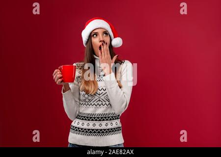 Close up portrait beautifiul caucasian woman in red Santa hat on red studio background. Christmas New Year holiday concept. Girl teeth smiling positiv Stock Photo
