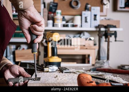 Carpenter screwing a hinge to a board with a screwdriver Stock Photo