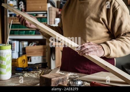 Carpenter looking at a wooden plank in a carpentry Stock Photo