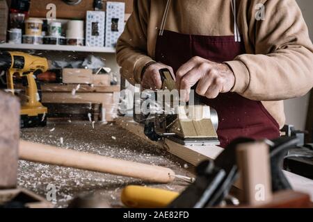 Carpenter working the wood with an electric brush Stock Photo