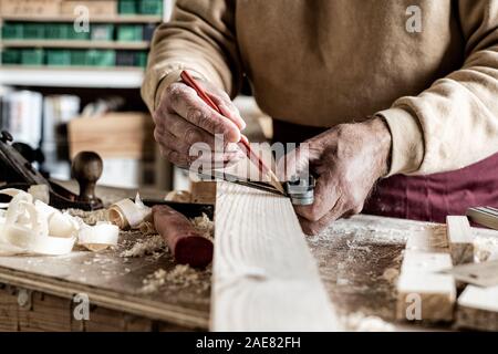 Carpenter making measurements with a pencil and a metal ruler on wooden plank Stock Photo