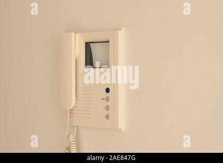 Video door phone with image on CRT display hanging on a wall. Hand holding handset. Video intercom equipment. Selective focus image. Stock Photo