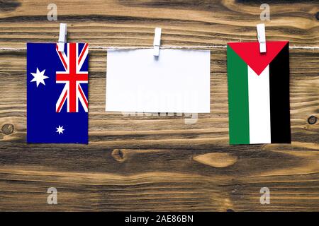 Hanging flags of Heard and Mcdonald Islands and Palestine attached to rope with clothes pins with copy space on white note paper on wooden background. Stock Photo
