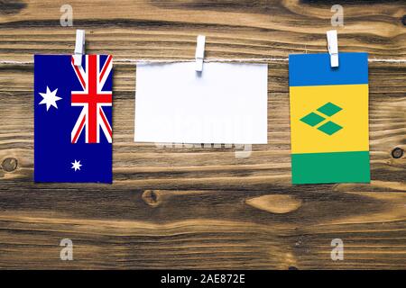 Hanging flags of Heard and Mcdonald Islands and Saint Vincent And The Grenadines attached to rope with clothes pins with copy space on white note pape Stock Photo