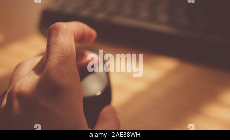 Female hand use computer mouse near keyboard, sunny desktop, selective focus on finger. Stock Photo