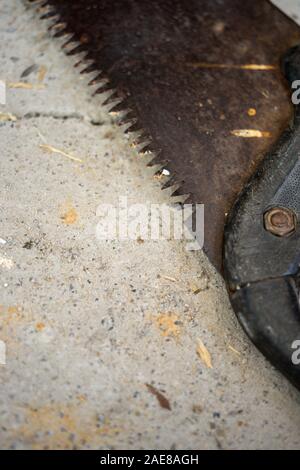 Old rusty saw on a stone floor, close-up. Stock Photo