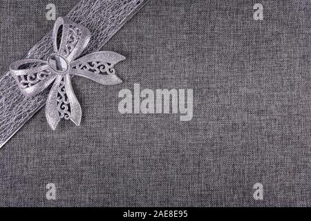Elegant shiny tied silver glitter bow on silver colored ribbon and on gray natural burlap. Horizontal greeting card background with large copy space a Stock Photo