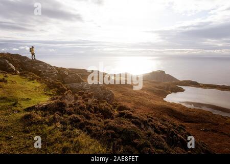 Woman standing on a rock with amazing view over the lake Lough O' Muilligan at Slieve League cliffs from Bunglass, County Donegal, Ireland Stock Photo
