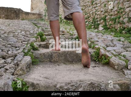 Male tourist walks barefoot on stone steps, close-up Stock Photo
