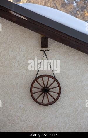 the wheel hangs on chain as wall decoration. Stock Photo