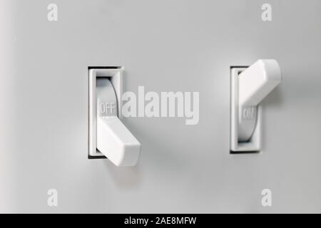 Closeup of white light switch turned off and another turned on in background with duplex wall plate. Concept of energy savings and conservation Stock Photo